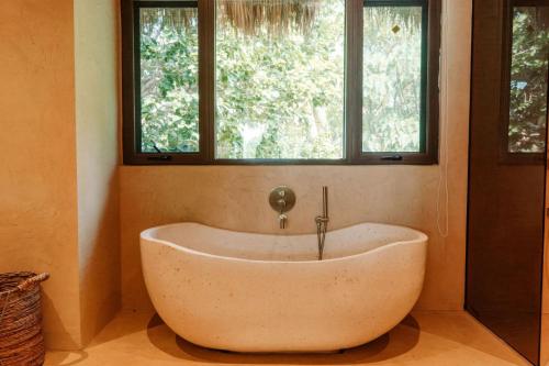 a bath tub in a room with two windows at Sunset at Las Cabanas in El Nido