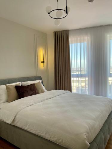 a bedroom with a large white bed with a window at Cashmere Apartment in Cluj-Napoca