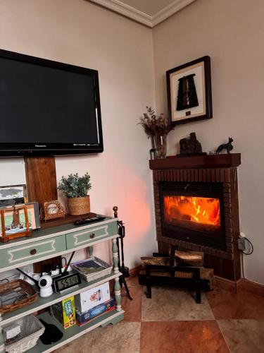 a living room with a fireplace and a flat screen tv at Casa Pichi in El Pulliu