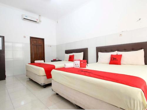 two beds in a room with red and white at RedDoorz @ Seturan Raya in Yogyakarta