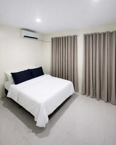 a white bedroom with a large white bed with blue pillows at Ben & Ben - Unit 2 in Cebu City