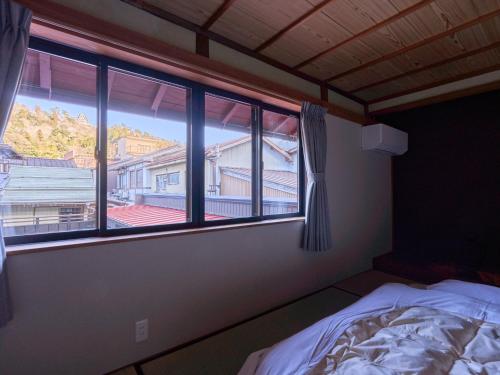 a bedroom with a bed and a window with a view at The Cross Inn Gujo in Gujo