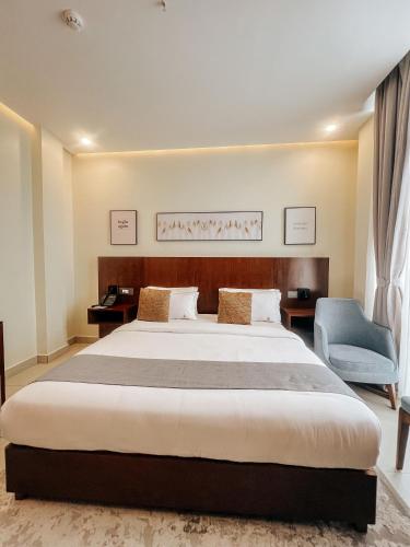 a bedroom with a large bed and a blue chair at Zabibu Hotel in Dodoma