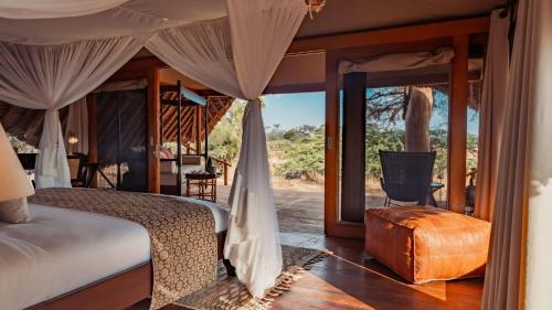 a bedroom with a bed with a view of a yard at Soroi Larsens Camp in Buffalo Springs  National Reserve