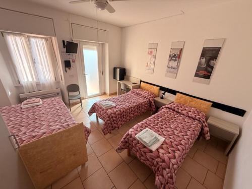 a large room with two beds and a television at Albergo Roma in Gattico