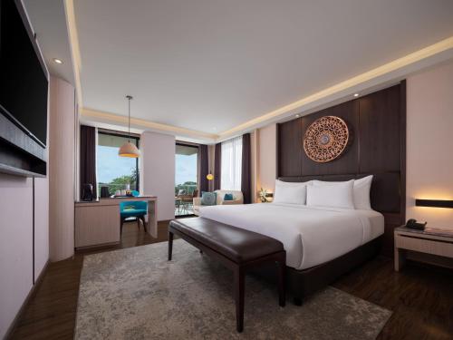 a bedroom with a large white bed and a desk at The Manohara Hotel Yogyakarta in Yogyakarta