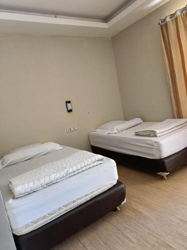 two beds in a small room withermottermott at Uciek Tengger Hotel Bromo in Ngadisari