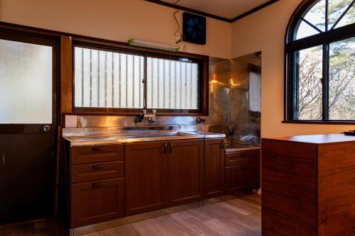 a kitchen with a sink and two windows at -貸切別荘-源泉かけ流し温泉 あずみ野ガレージヴィラ-1日1組限定- in Azumino