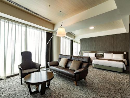 a hotel room with a bed and a couch and a table at KOKO HOTEL Premier Hakata in Fukuoka