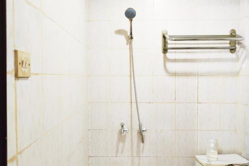 a shower in a white tiled bathroom at NamRoom at Margot Jaksa in Jakarta