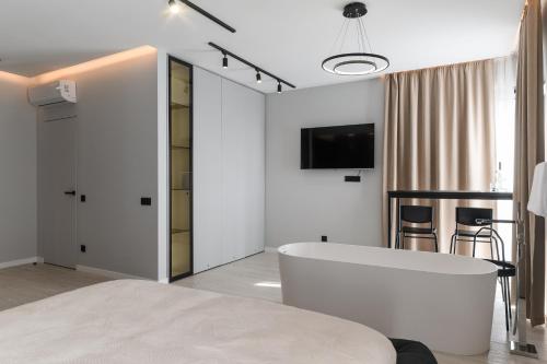 a white bedroom with a tub and a tv on the wall at MM GROUP APARTMENT Dastor in Uzhhorod