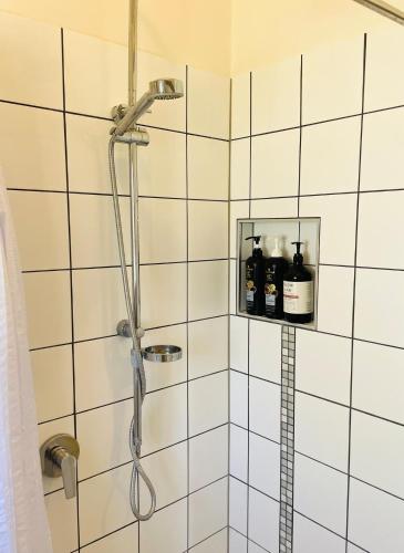 a shower in a bathroom with white tiles at The Mango Shack in Carnarvon