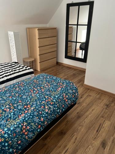 a bedroom with a bed and a dresser and a mirror at Dans ma Campagne in Mecquignies