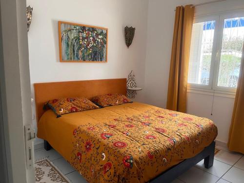 a bedroom with a bed with a comforter and a window at Residence Dar Yasmina in Mezraya