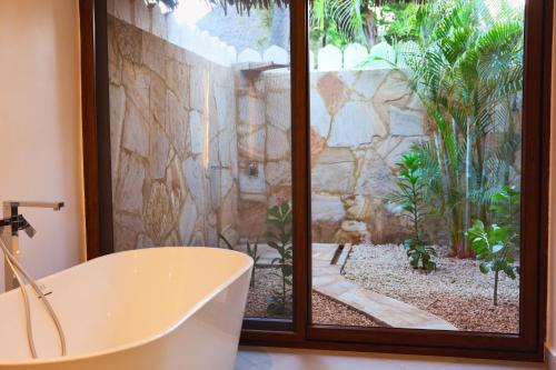 a bath tub in a bathroom with a stone wall at Bluebay Beach Resort & Spa in Kiwengwa
