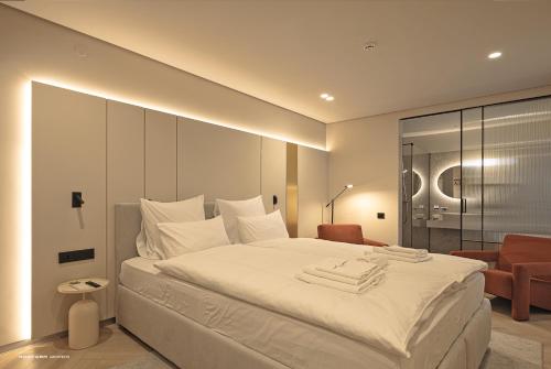 ein Schlafzimmer mit einem großen weißen Bett und einem Stuhl in der Unterkunft Hotel Laudon in Uschhorod