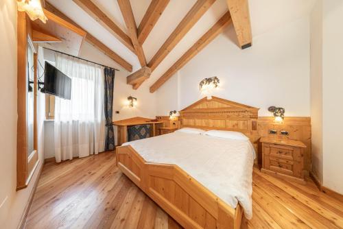a bedroom with a large bed and wooden floors at Family Hotel La Perla in Fiera di Primiero