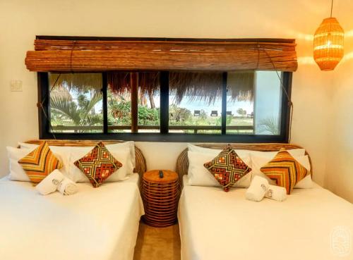 two beds in a room with a window at Sunset at Las Cabanas in El Nido