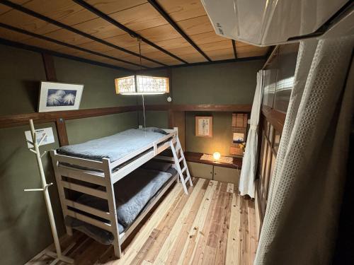 a bedroom with a bunk bed in a room at ゲストハウス あめりか和 in Namerikawa