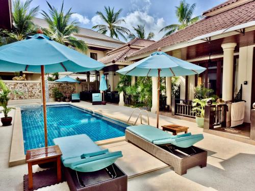 a swimming pool with two chairs and umbrellas at Sibaja Palms Sunset Beach Luxury Apartments in Taling Ngam Beach