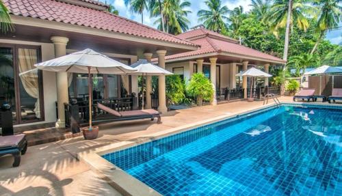 a swimming pool in front of a house at Sibaja Palms Sunset Beach Luxury Apartments in Taling Ngam Beach