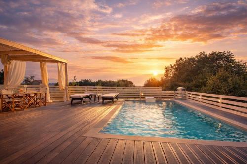 a pool on a deck with a sunset in the background at Casa Campanario Villa - Charming Nature Villa with Pool in a Picturesque Village By Villa Mana Gers in Agios Leon