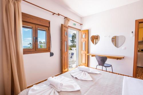 a bedroom with a bed and a chair and a window at Enalia Suites in Amoopi