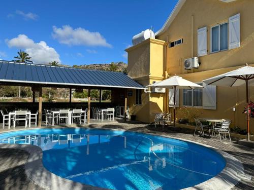 a swimming pool in front of a building with tables and chairs at Korail Bleu in Rodrigues Island