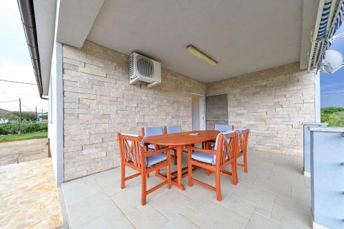 a wooden table with chairs and a television on a patio at Eda in Vrsi