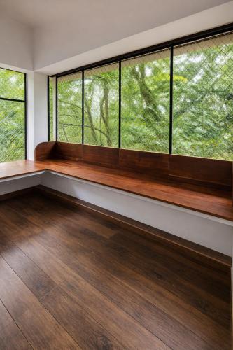 an empty room with large windows and wood floors at MAK Mansion in Kotikulam