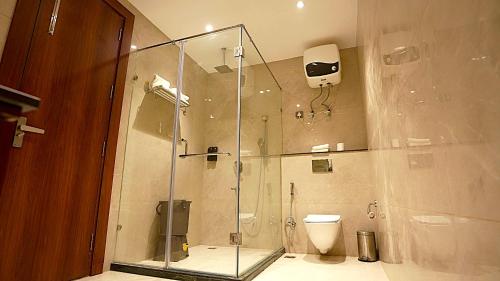 a bathroom with a glass shower with a toilet at Tivoli Bijwasan in Jāmb