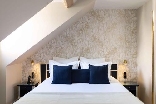 a bedroom with a white bed with blue pillows at Queen Mary Opera in Paris