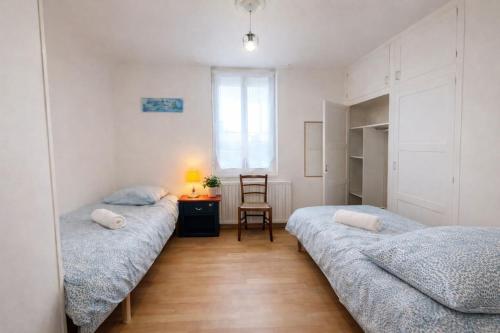 two beds in a room with a table and a chair at Maison entière pour 4 personnes avec parking proche centre ville in Saint-Sulpice-sur-Risle