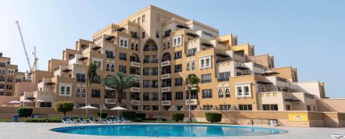 a large apartment building with a pool in front of it at Live and experience Al Marjan Island 1BR in Ras al Khaimah