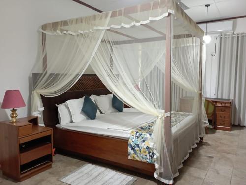 a bedroom with a canopy bed with white curtains at Country Homes Srilanka in Mount Lavinia