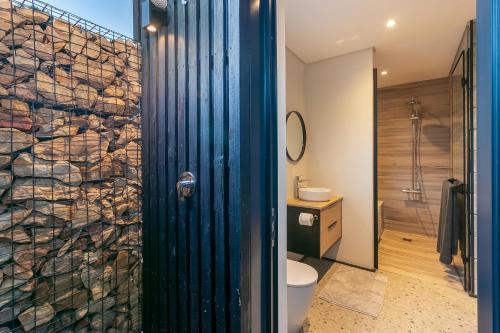 a bathroom with a toilet and a glass shower door at Knysna Tsukamori in Knysna