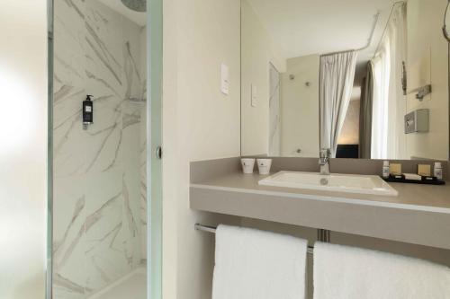 a white bathroom with a sink and a mirror at Queen Mary Opera in Paris