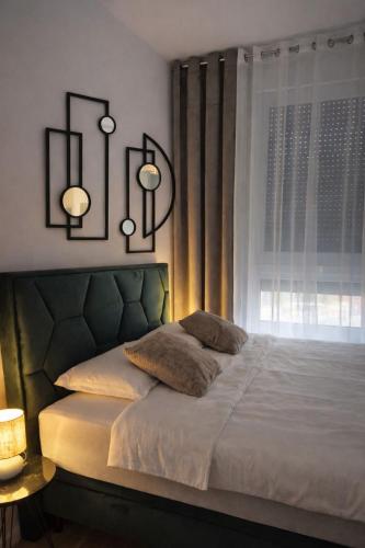 a bedroom with a large bed with a window at Una Apartmani Musique in Tuzla