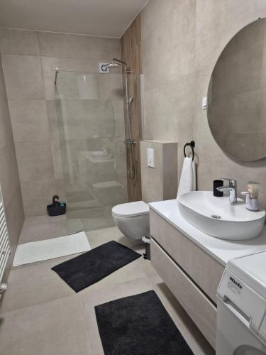 a bathroom with a shower and a toilet and a sink at Una Apartmani Musique in Tuzla