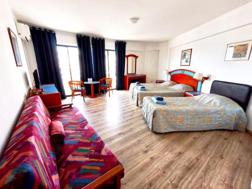 a hotel room with two beds and a couch at Petalmo City Apartments in Larnaca
