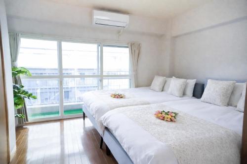 two beds in a room with a large window at Sengakuji 602, 40 square meters house Direct train from the airport in Tokyo