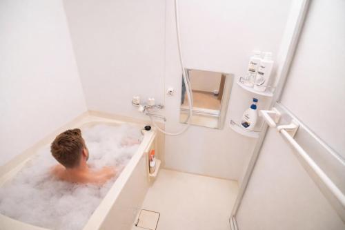 a man is in a bath tub in a bathroom at Sengakuji 602, 40 square meters house Direct train from the airport in Tokyo