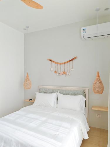 a bedroom with a white bed with white sheets at The Shores House-Royal Plams Tres by THE HOUSE in Dauis
