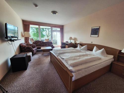 a hotel room with a large bed and a couch at Hotel Hahnenkleer Hof in Hahnenklee-Bockswiese