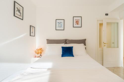 a bedroom with a white bed with a blue pillow at Suite Des Etrangers -Parcheggio privato- Private parking in Sanremo