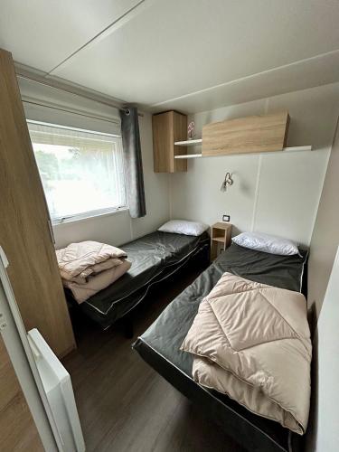 a small room with two beds and a window at Mobilhome les 3C de mimizan in Mimizan