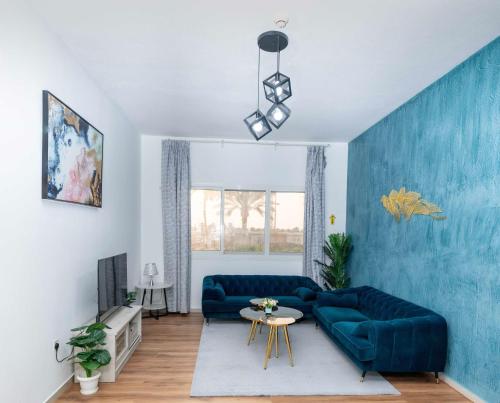 a living room with a blue couch and a table at Live so close to beach - Al Marjan Island in Ras al Khaimah