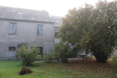 une vieille maison avec des arbres devant dans l'établissement Le Chai, à La Celle-sous-Gouzon