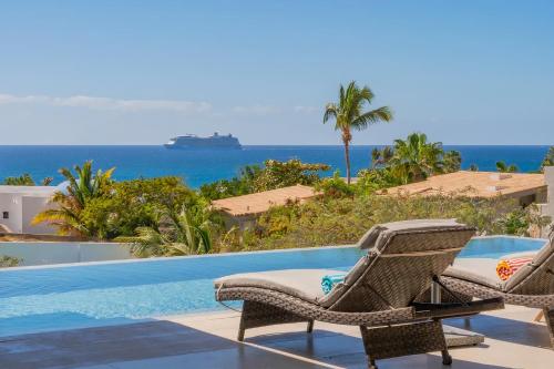 a pool with two chairs and a cruise ship in the ocean at Villa Real para 12 personas con piscina privada in Cabo San Lucas