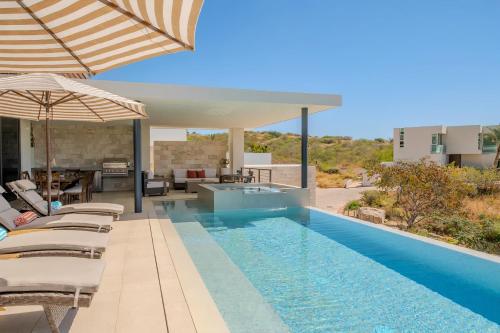 a swimming pool with lounge chairs and umbrellas at Villa Real para 12 personas con piscina privada in Cabo San Lucas